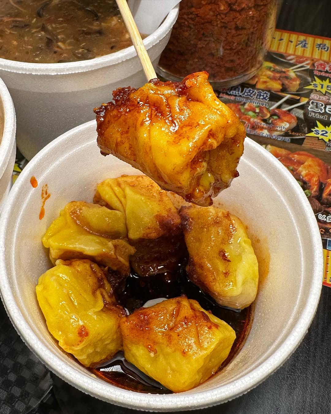 Street-style siu mai dumplings in a paper bowl with sauce