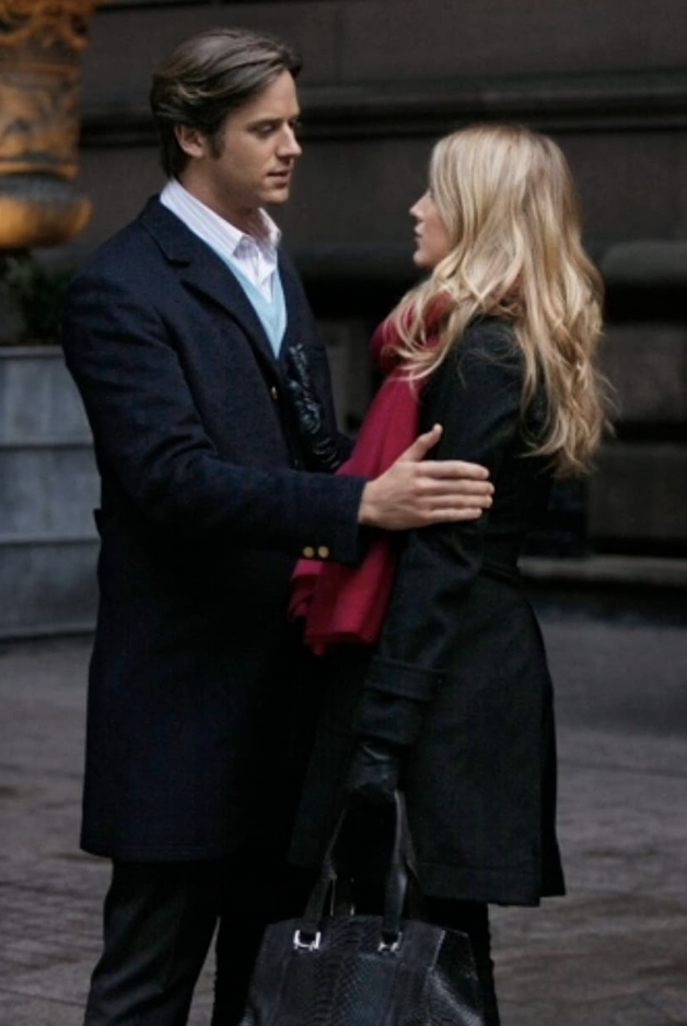 Serena van der Woodsen in a black coat and red scarf talking to Gabriel Edwards